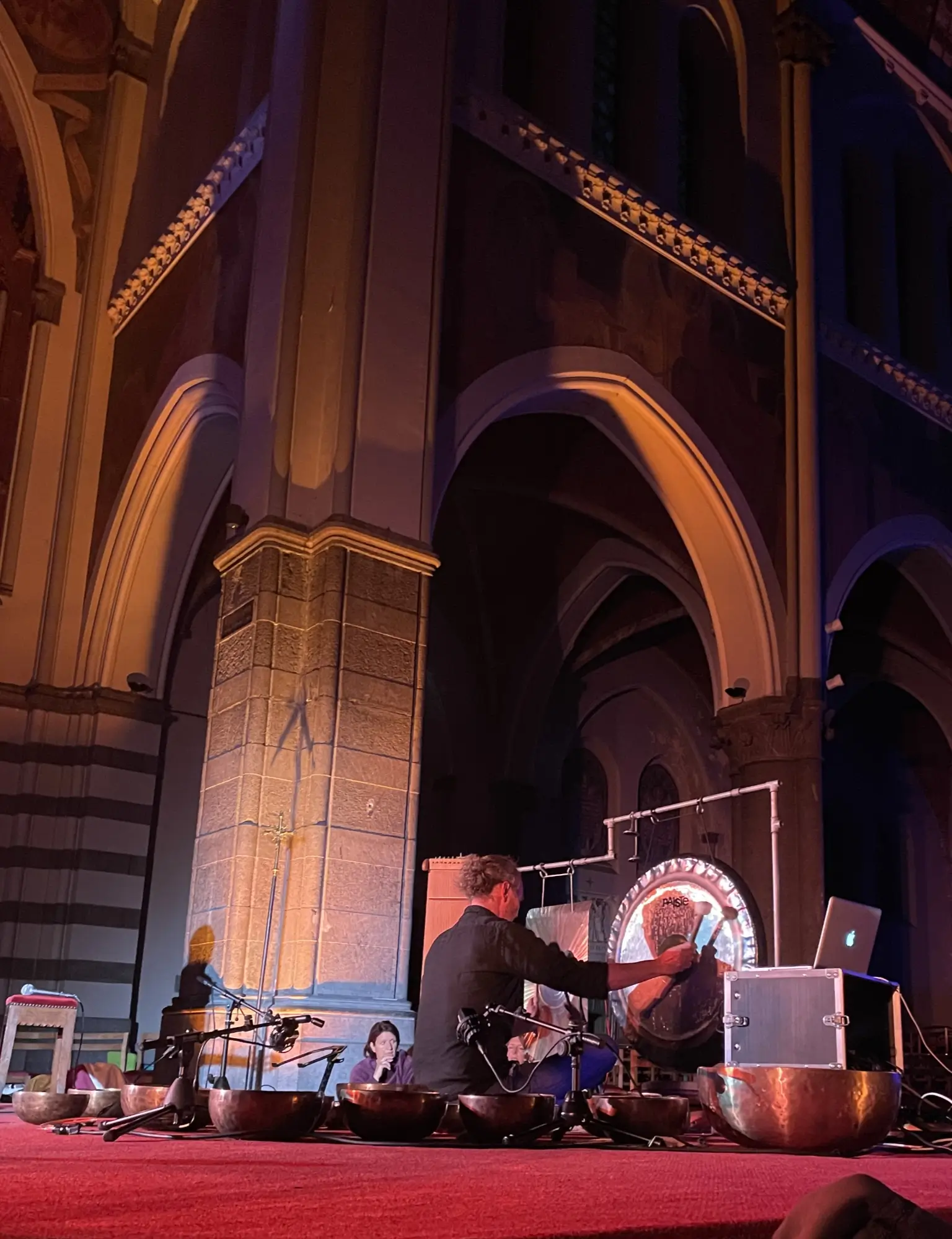 Gil Delogne joue des gongs et des bols sur le podium à l'occasion de LEVITATION 360° dans l'église Sainte-Julienne à Verviers.