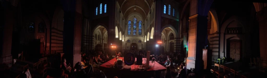 Photo panoramique du setup de LEVITATION 360 ° dans la pénombre. On voit le soleil qui se couche dans le vitraux de l'église Sainte-Julienne de Verviers.